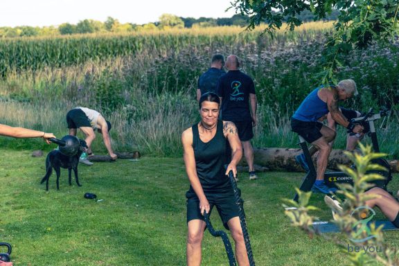 Gruppentraining im Freien mit mehreren Personen und Hunden, umgeben von Natur.