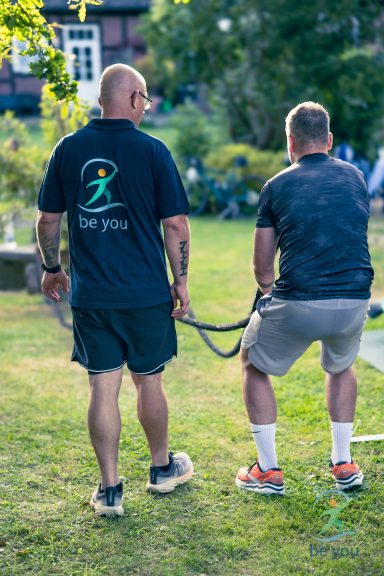 Zwei Männer im Garten, einer hält eine Leine, während der andere assistiert.
