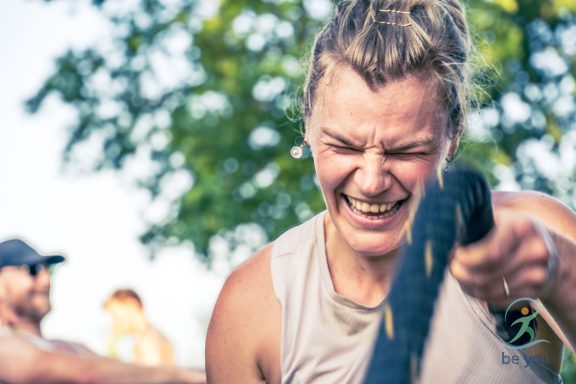 Junge Frau beim Sport, lächelt und zieht an einem Seil mit Freude und Enthusiasmus.