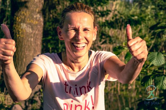 Lächelnde Person mit Daumen hoch, trägt ein rosa T-Shirt mit der Aufschrift "think pink!"