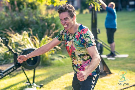 Mann in farbigem Shirt beim Sport im Freien, lächelt und bewegt sich aktiv.