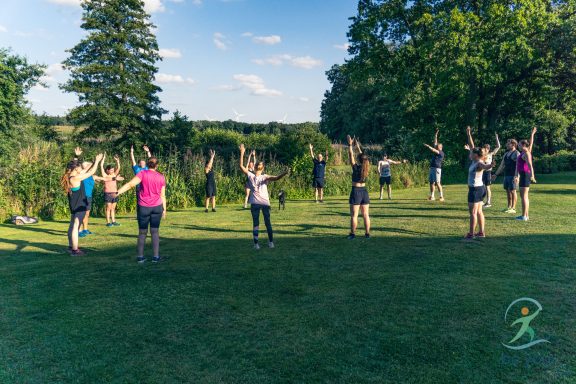 Gruppe von Menschen beim Outdoor-Workout in einem grünen Park.