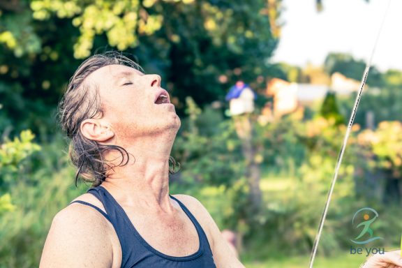 Eine Person mit grünem Hintergrund, die den Kopf zurücklegt und intensiv nach oben blickt.